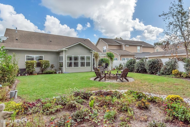 back of house featuring a fire pit and a lawn