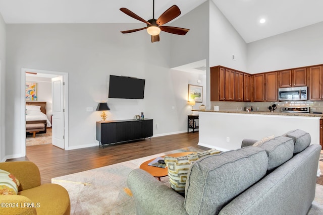 living room featuring dark hardwood / wood-style flooring, high vaulted ceiling, and ceiling fan