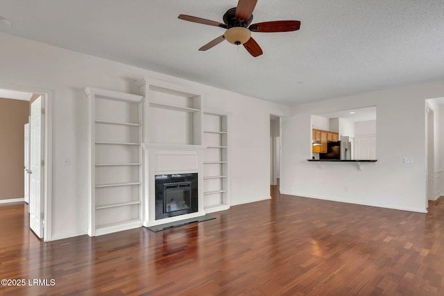 34 Basket Walk Dr, Okatie, SC 29909 - unfurnished living room featuring built in features, a glass covered fireplace, baseboards, a ceiling fan, and dark wood finished floors