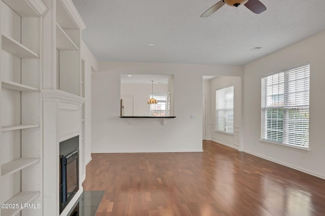 34 Basket Walk Dr, Okatie, SC 29909 - unfurnished living room with a textured ceiling, a glass covered fireplace, a ceiling fan, baseboards, and dark wood-style floors