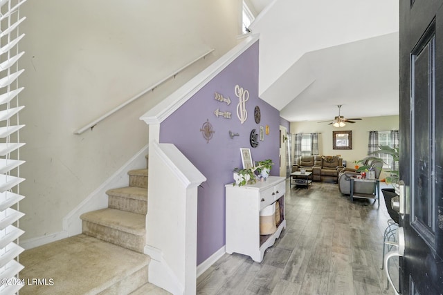 staircase with ceiling fan, hardwood / wood-style floors, and a high ceiling