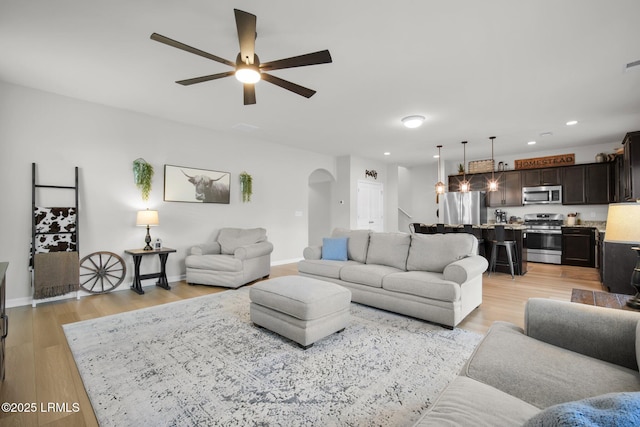 living area with light wood-style floors, baseboards, arched walkways, and recessed lighting