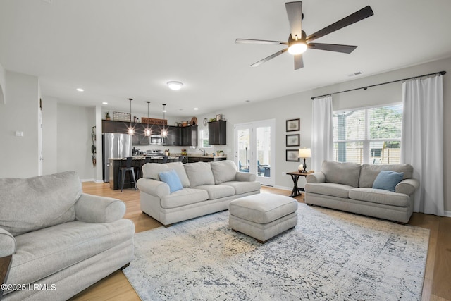 living room with recessed lighting, visible vents, light wood-style flooring, and baseboards