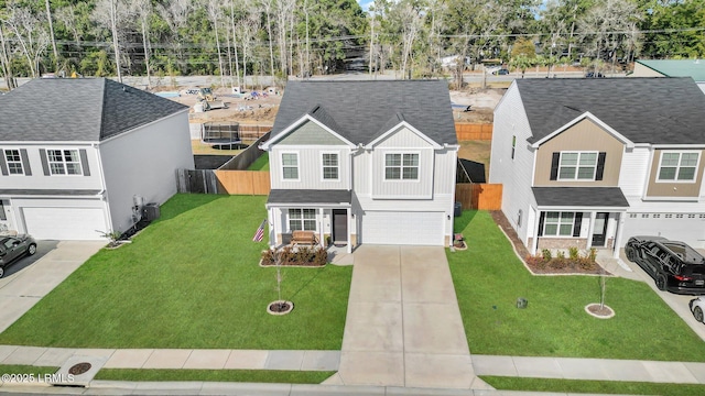 traditional-style house with concrete driveway, board and batten siding, fence, a garage, and a front lawn