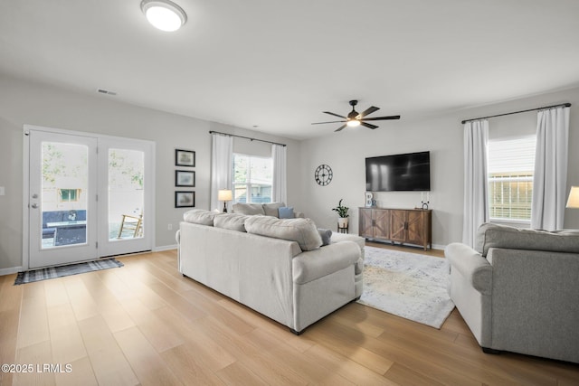 living area featuring ceiling fan, light wood-style flooring, and baseboards