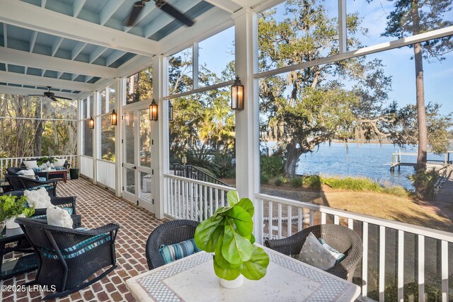 sunroom with beamed ceiling, a water view, and ceiling fan