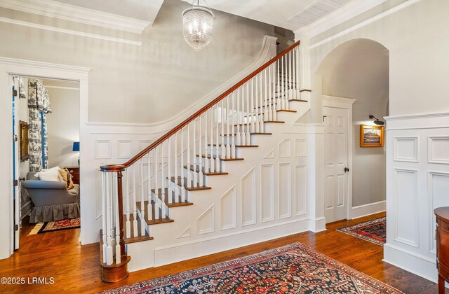 stairway featuring a notable chandelier, hardwood / wood-style flooring, and ornamental molding