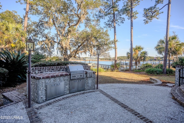 view of patio / terrace featuring grilling area, a water view, and exterior kitchen