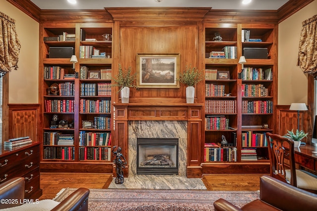 living area with ornamental molding, hardwood / wood-style floors, built in features, and a fireplace