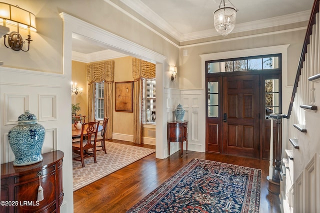 foyer entrance with ornamental molding, dark hardwood / wood-style floors, and a notable chandelier