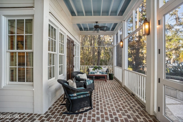 sunroom with ceiling fan and beam ceiling