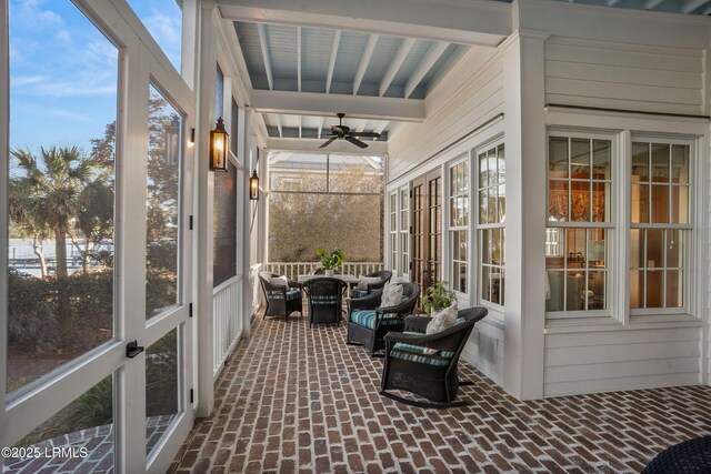 sunroom with ceiling fan and beam ceiling