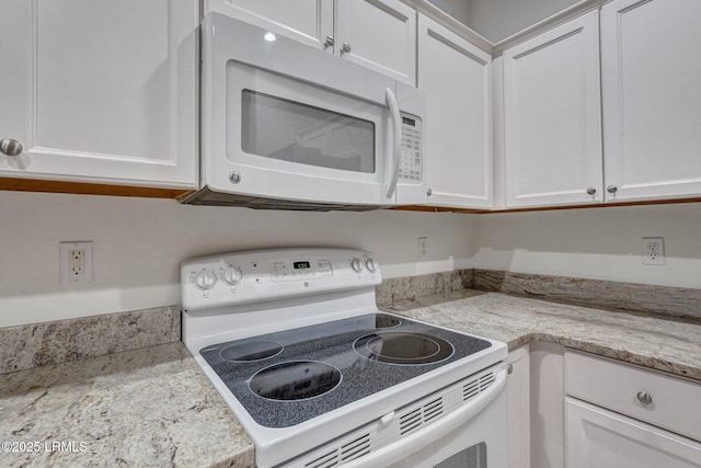 kitchen featuring light stone countertops, white cabinets, and white appliances