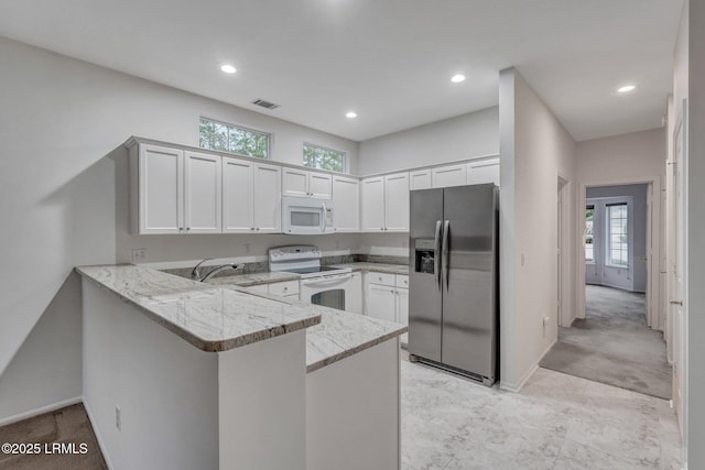 kitchen featuring white cabinetry, light stone counters, white appliances, and kitchen peninsula