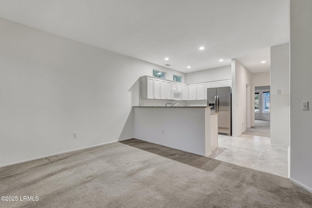 kitchen with white cabinetry, light colored carpet, kitchen peninsula, and stainless steel refrigerator with ice dispenser