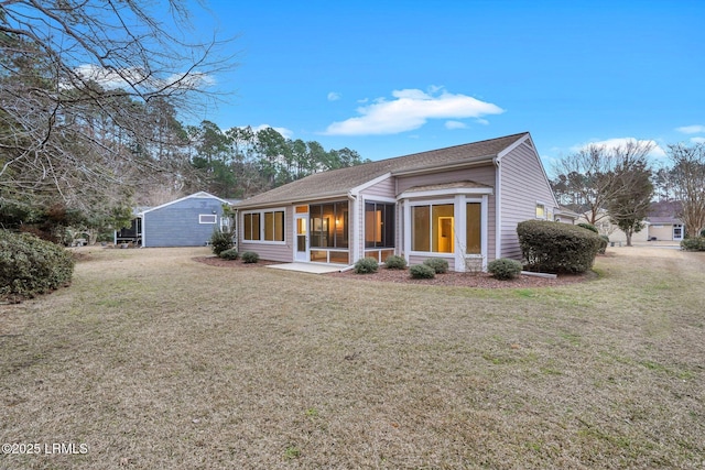 rear view of house featuring a yard and a sunroom