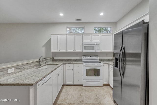 kitchen with white cabinetry, sink, kitchen peninsula, light stone countertops, and white appliances