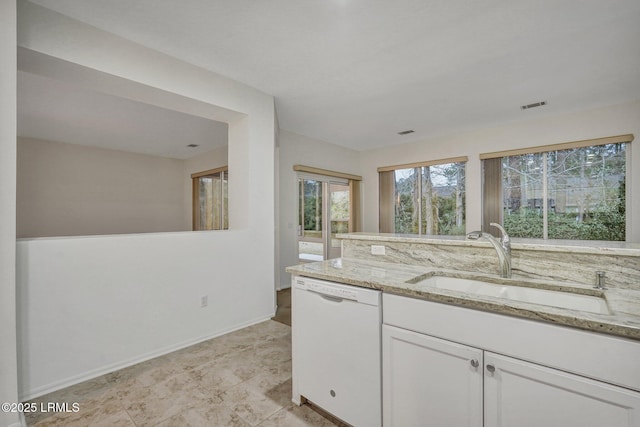 kitchen with white cabinetry, white dishwasher, light stone countertops, and sink