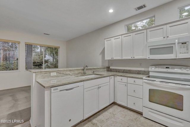 kitchen with white appliances, kitchen peninsula, sink, and white cabinets