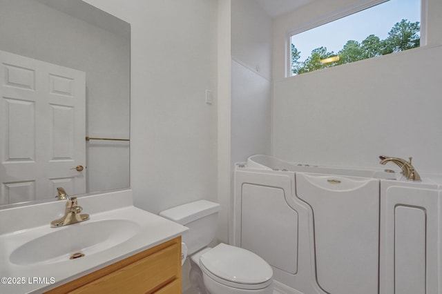 bathroom with vanity, a tub, and toilet