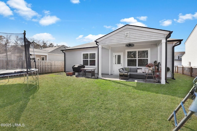 rear view of house with a trampoline, a lawn, and a patio area