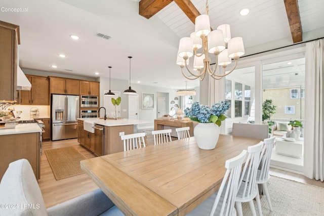 dining space featuring lofted ceiling with beams, a chandelier, and light hardwood / wood-style floors