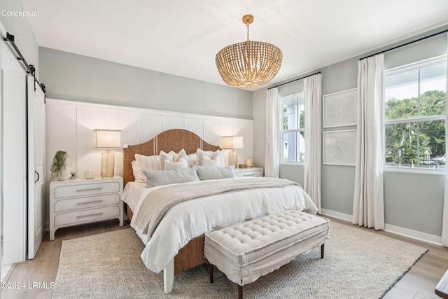 bedroom featuring a barn door and light hardwood / wood-style flooring