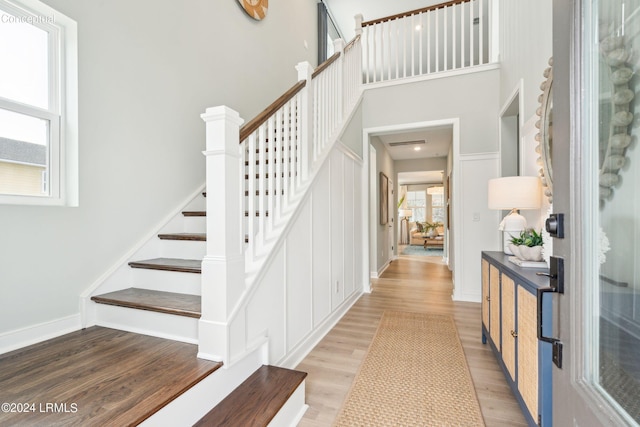 staircase with wood-type flooring and a towering ceiling