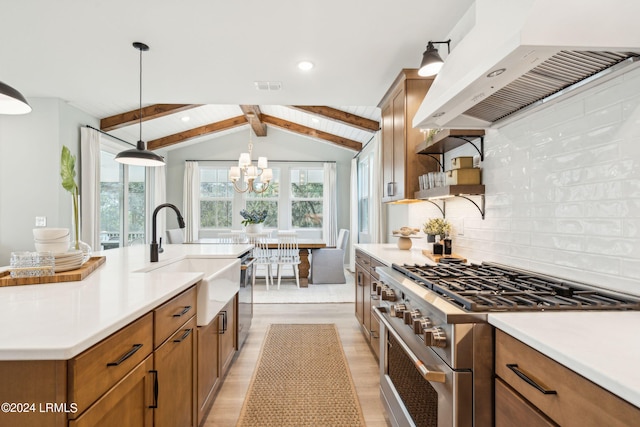 kitchen featuring sink, appliances with stainless steel finishes, vaulted ceiling with beams, custom range hood, and decorative light fixtures