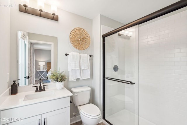 bathroom featuring a shower with door, vanity, and toilet