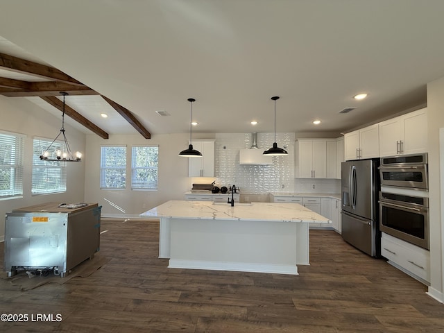 kitchen featuring pendant lighting, appliances with stainless steel finishes, white cabinetry, backsplash, and an island with sink