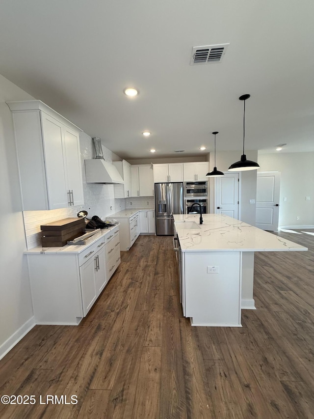 kitchen featuring custom exhaust hood, an island with sink, appliances with stainless steel finishes, and white cabinets