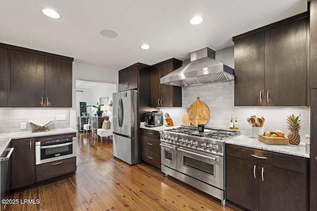 17 Audubon Rd, Ladys Island, SC 29907 - kitchen with stainless steel appliances, wall chimney exhaust hood, dark brown cabinets, decorative backsplash, and recessed lighting