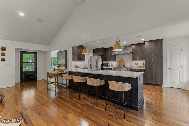 17 Audubon Rd, Ladys Island, SC 29907 - kitchen with dark brown cabinetry, hardwood / wood-style floors, a breakfast bar area, high vaulted ceiling, and tasteful backsplash