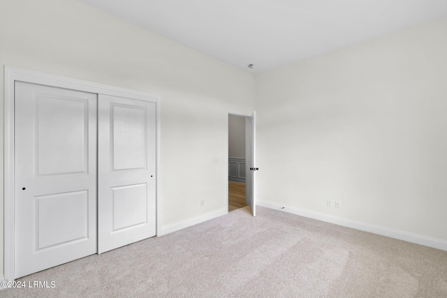 unfurnished bedroom featuring light colored carpet and a closet