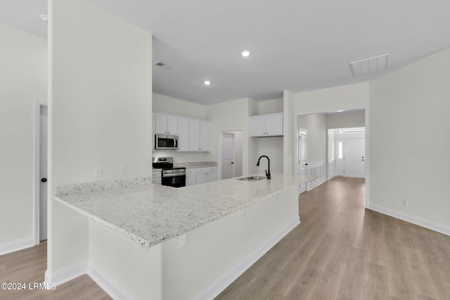 kitchen featuring sink, appliances with stainless steel finishes, a kitchen breakfast bar, kitchen peninsula, and white cabinets