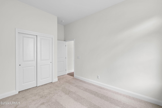 unfurnished bedroom featuring light colored carpet and a closet