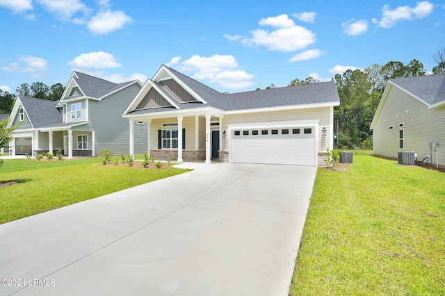 craftsman house with a garage, central air condition unit, covered porch, and a front lawn