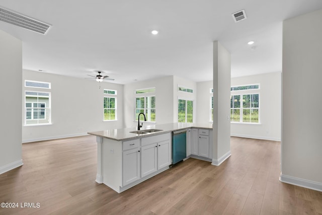 kitchen with sink, stainless steel dishwasher, white cabinets, and light hardwood / wood-style flooring