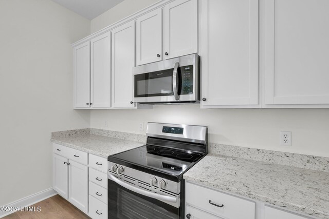 kitchen featuring white cabinetry, light stone counters, and appliances with stainless steel finishes