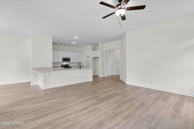 unfurnished living room with ceiling fan, light hardwood / wood-style floors, and sink