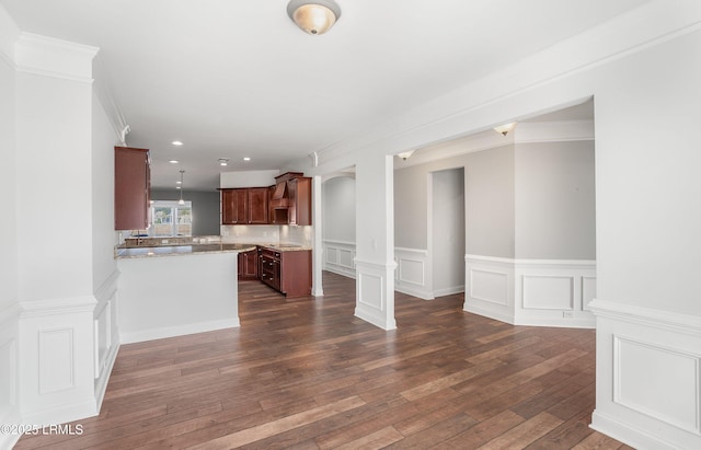 interior space featuring light stone countertops, crown molding, dark wood-type flooring, and decorative columns