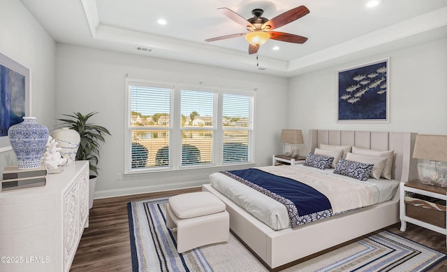 bedroom featuring dark hardwood / wood-style flooring, a tray ceiling, and ceiling fan