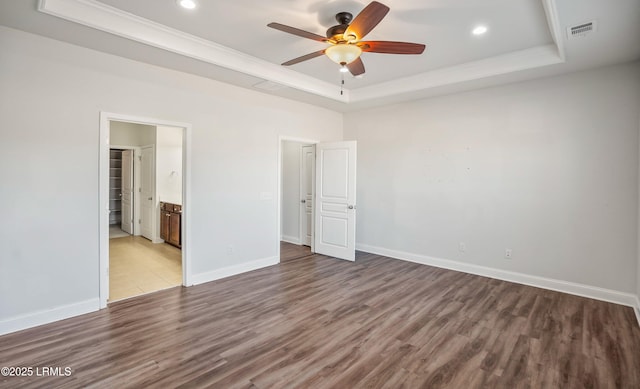 unfurnished bedroom featuring crown molding, ensuite bathroom, light hardwood / wood-style floors, and a tray ceiling