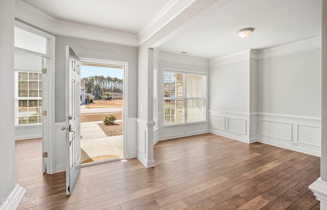 interior space with hardwood / wood-style floors, ornamental molding, and a healthy amount of sunlight