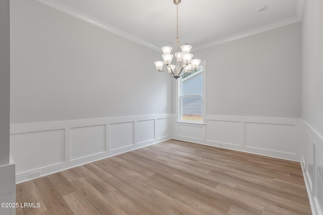 41 Fairfield Rd, Beaufort, SC 29907 - unfurnished dining area with crown molding, a wainscoted wall, light wood-type flooring, and a chandelier