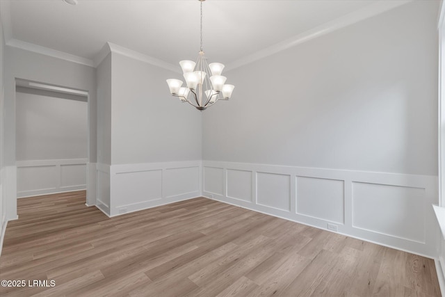 41 Fairfield Rd, Beaufort, SC 29907 - unfurnished dining area with a notable chandelier, ornamental molding, light wood finished floors, and a wainscoted wall