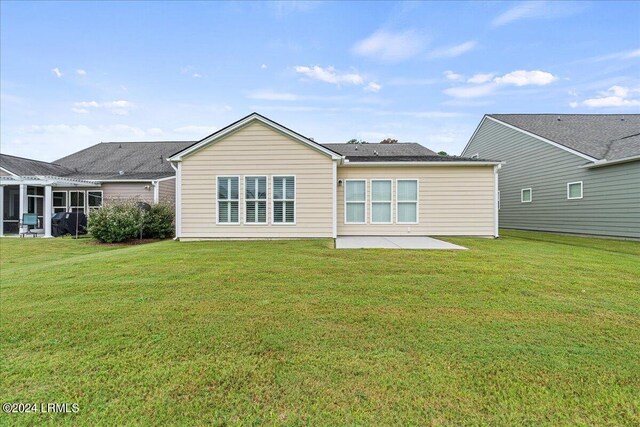 back of property with a yard and a patio