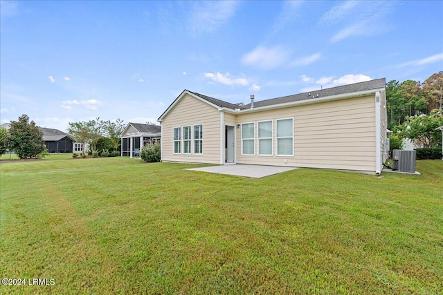 rear view of property with cooling unit, a yard, and a patio area