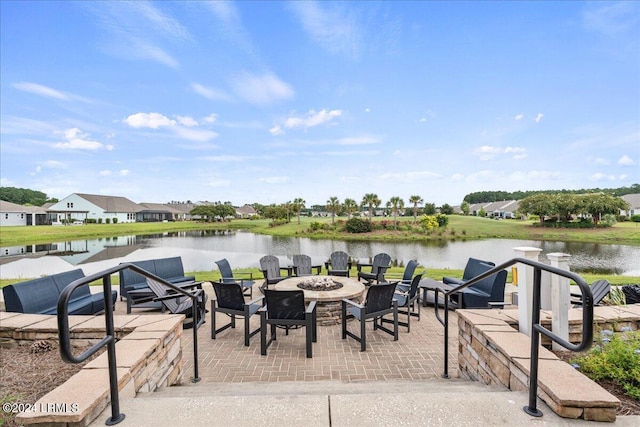 view of dock with a water view, an outdoor fire pit, and a patio area